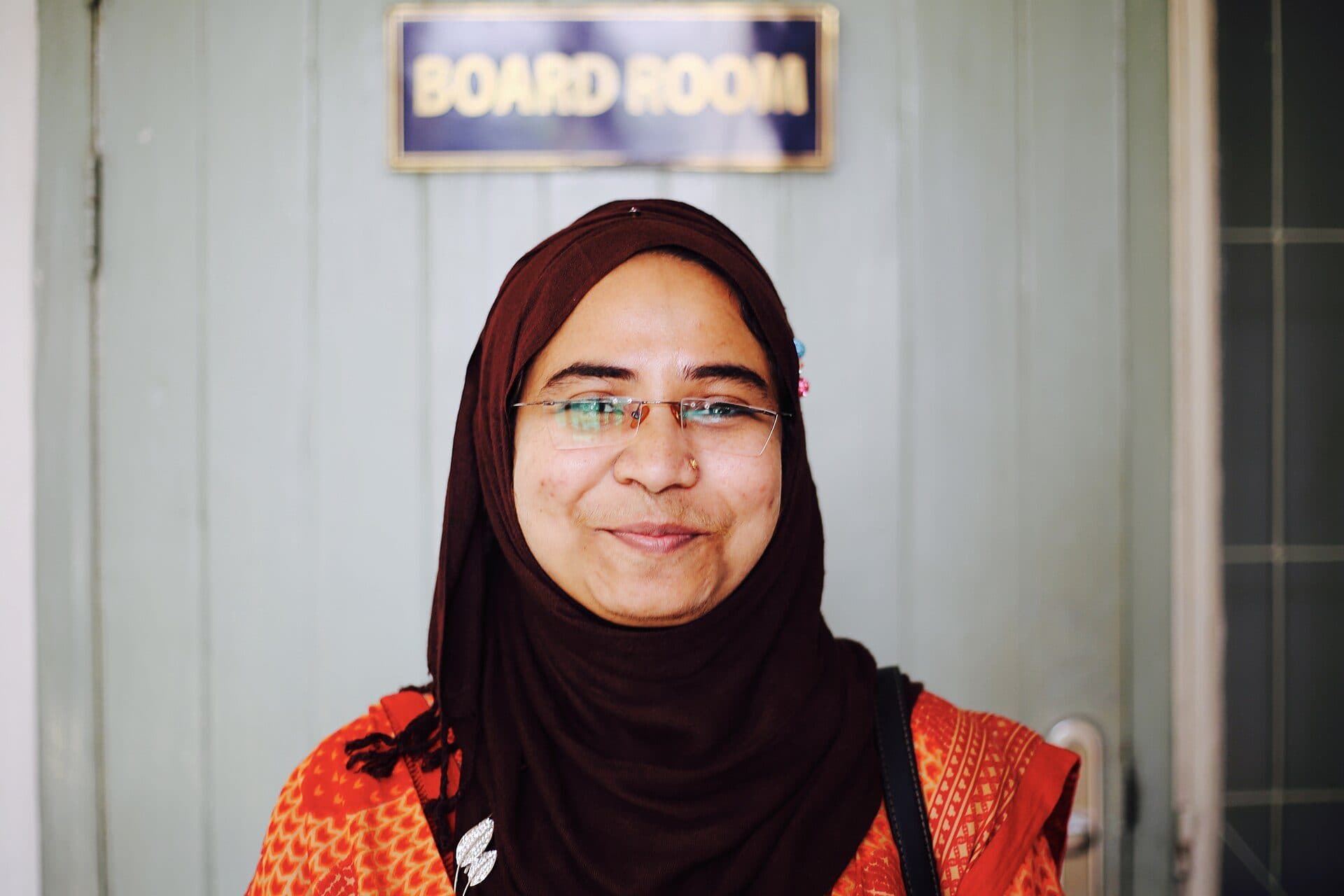 A young professional woman smiling outside a board room